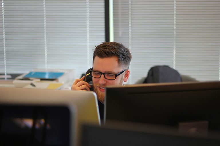 Man using phone to call in front of his computer